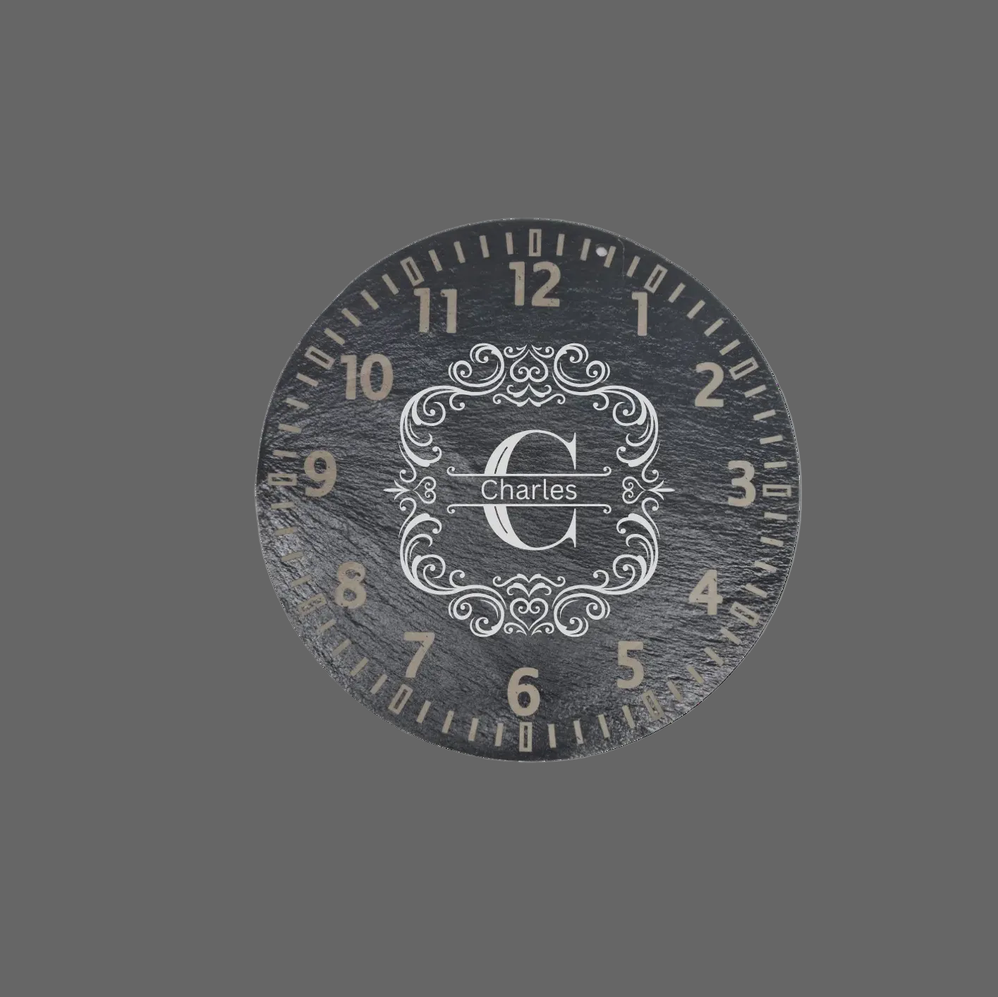 A round dark gray slate wall clock with a distressed finish, featuring numerals and a central monogrammed crest with the name 'charles' in script.