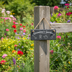 A rectangular black hanging sign with the words 'Grandma's Garden' and small drawings of gardening tools and a plant, suspended by a natural twine loop.