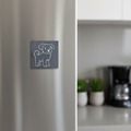 A square dark gray slate fridge magnet featuring a simple white line-art illustration of a puppy.